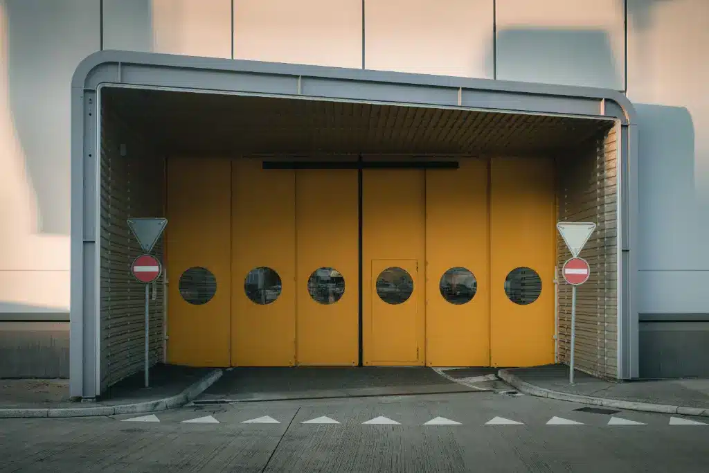 Industrial loading bay with yellow sliding doors, circular windows, and no-entry traffic signs