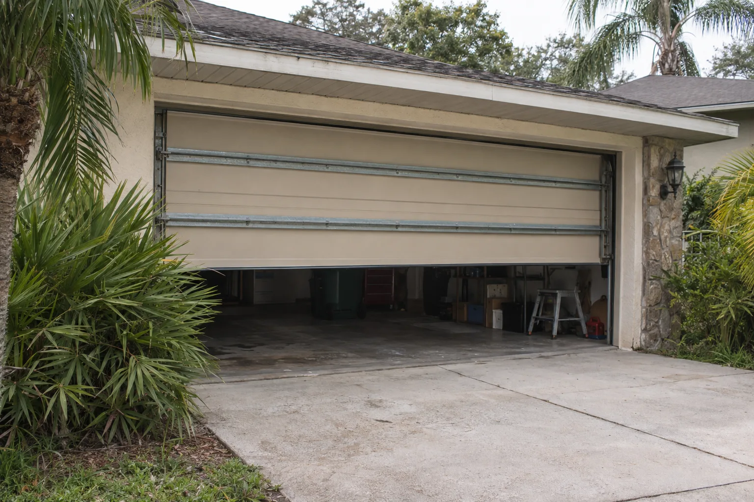 A reinforced steel hurricane-rated garage door on a single-story Orlando home, with horizontal bracing struts visible across the door sections, surrounded by Florida palm landscaping under bright daylight